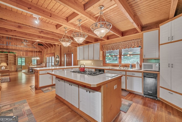 kitchen with kitchen peninsula, decorative light fixtures, a kitchen island, white cabinetry, and stainless steel gas cooktop