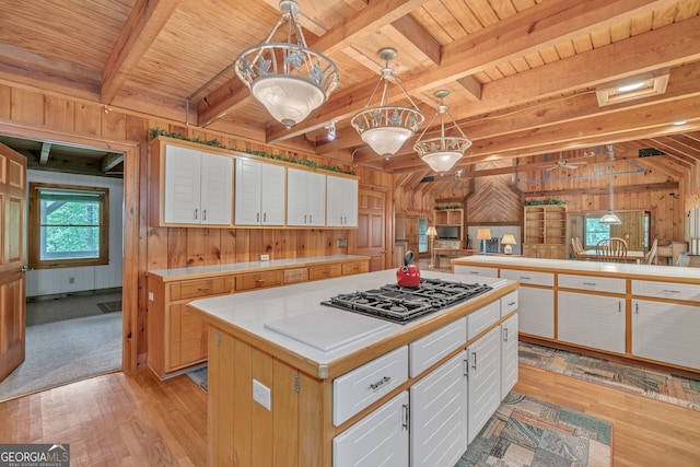 kitchen with white cabinets, pendant lighting, and wood walls