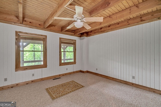 carpeted empty room featuring beamed ceiling, ceiling fan, and wooden walls