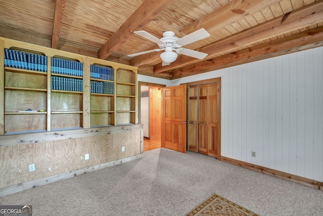 unfurnished room with light colored carpet, ceiling fan, wooden ceiling, beamed ceiling, and wood walls