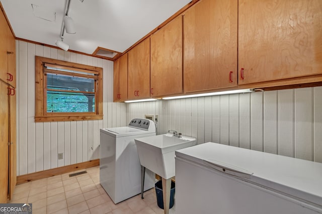 laundry area with sink, rail lighting, cabinets, wood walls, and washer / dryer