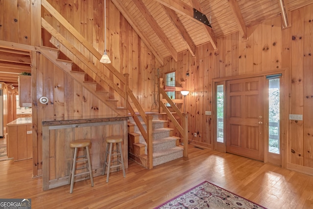 entryway featuring beamed ceiling, wooden ceiling, wooden walls, and light hardwood / wood-style flooring