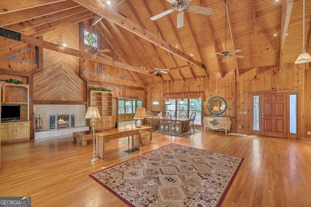 living room with wood walls, beamed ceiling, high vaulted ceiling, and wooden ceiling