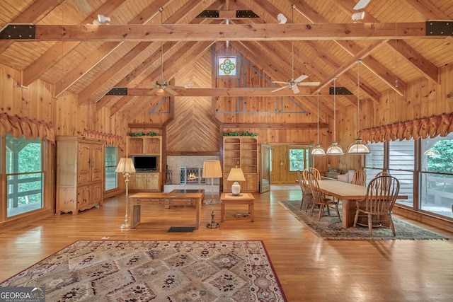 dining room featuring beam ceiling, high vaulted ceiling, and light hardwood / wood-style floors