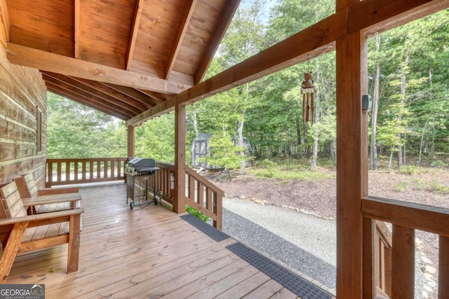 wooden deck featuring an outbuilding, a storage shed, grilling area, and a wooded view