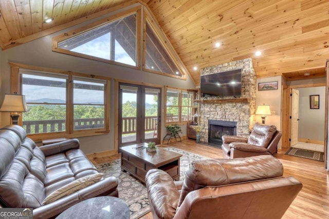 living room featuring wood ceiling, wood finished floors, and a stone fireplace