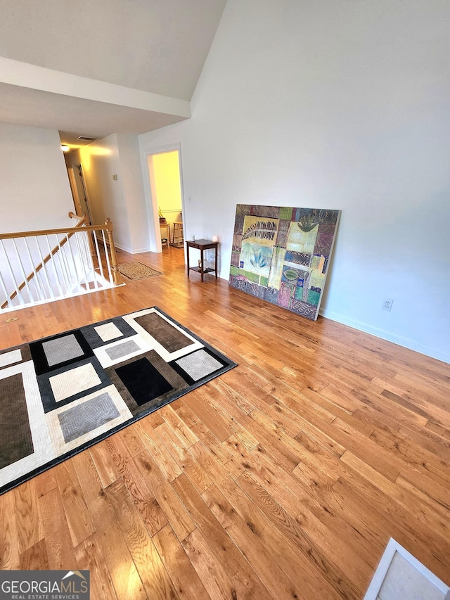 unfurnished living room with wood-type flooring and high vaulted ceiling