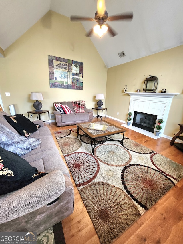 living room with vaulted ceiling, a fireplace, wood-type flooring, and ceiling fan