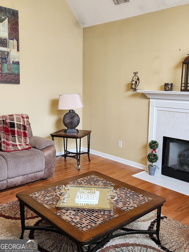 living room featuring hardwood / wood-style floors, a textured ceiling, and a tile fireplace