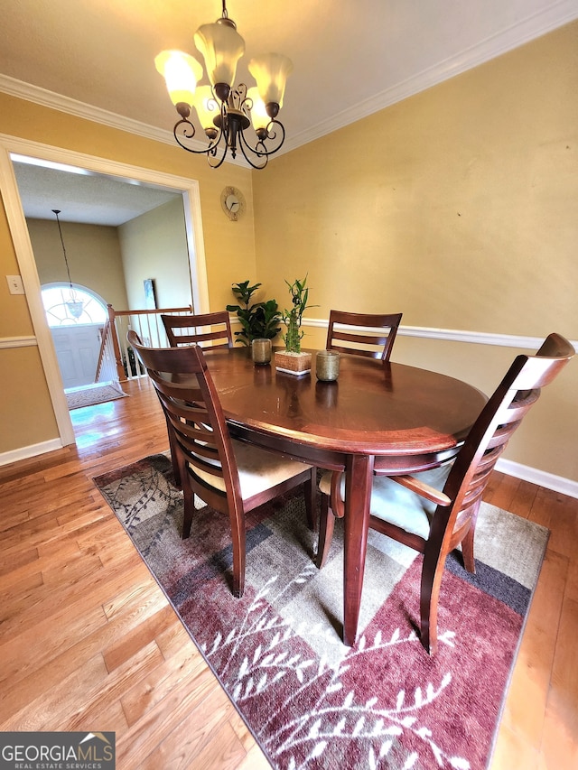 dining area with hardwood / wood-style floors, crown molding, and an inviting chandelier