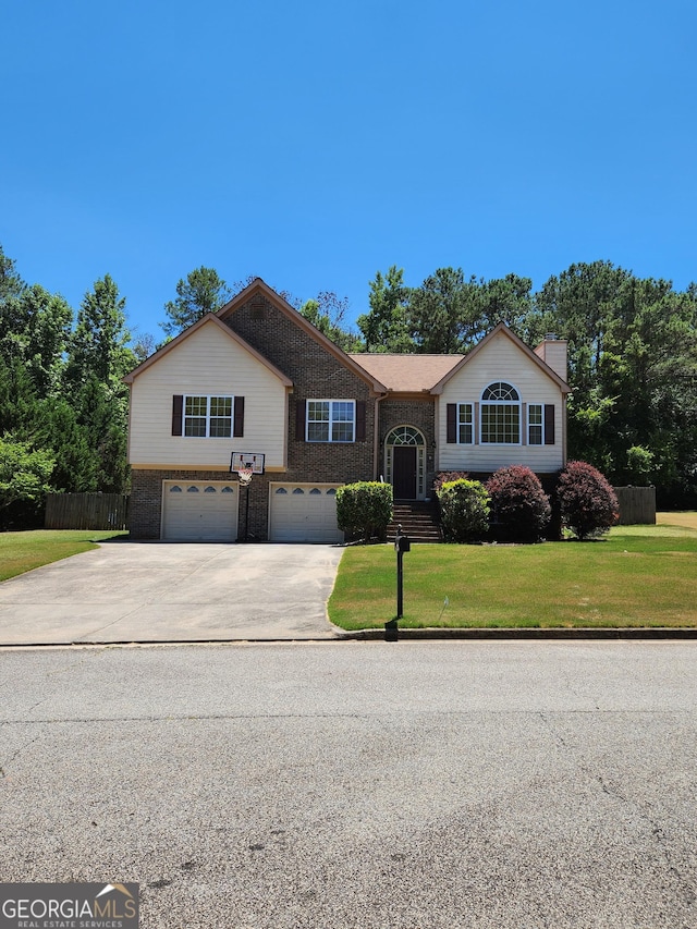 raised ranch with an attached garage, concrete driveway, brick siding, and a chimney