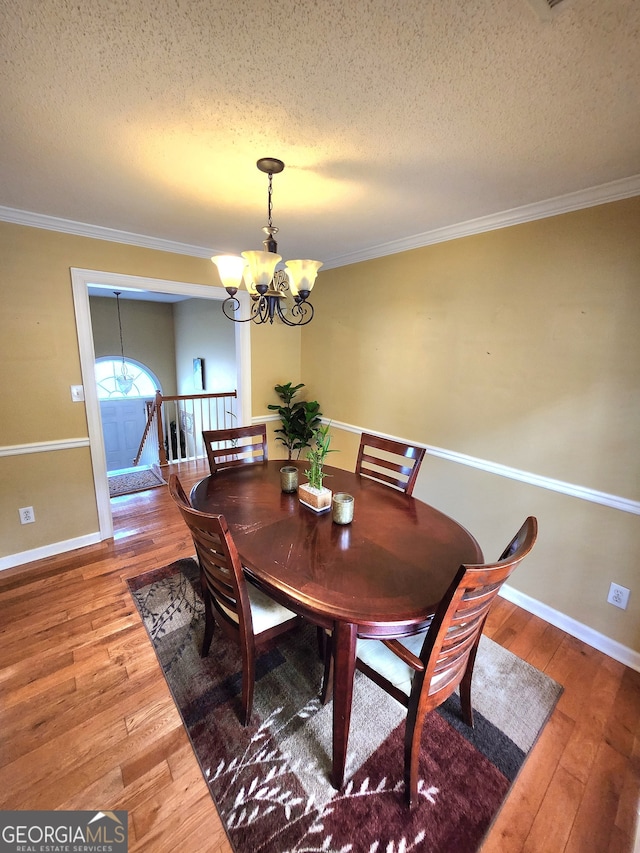 dining area featuring a notable chandelier, a textured ceiling, wood-type flooring, and crown molding