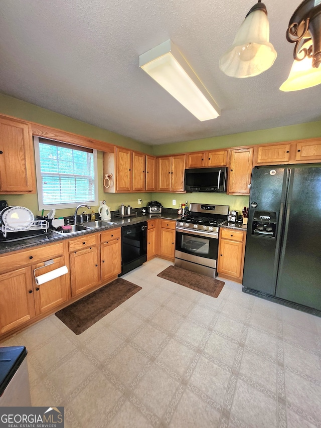 kitchen featuring decorative light fixtures, black appliances, sink, and a textured ceiling