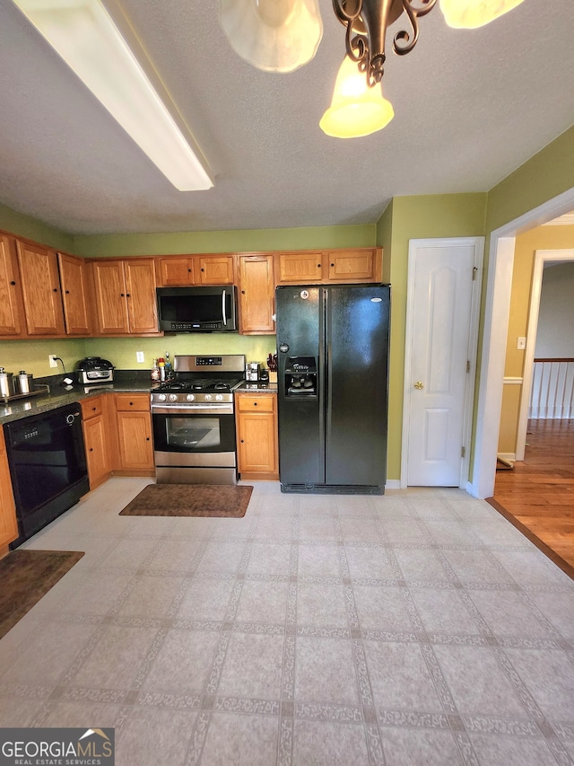 kitchen with a textured ceiling, black appliances, and light hardwood / wood-style flooring