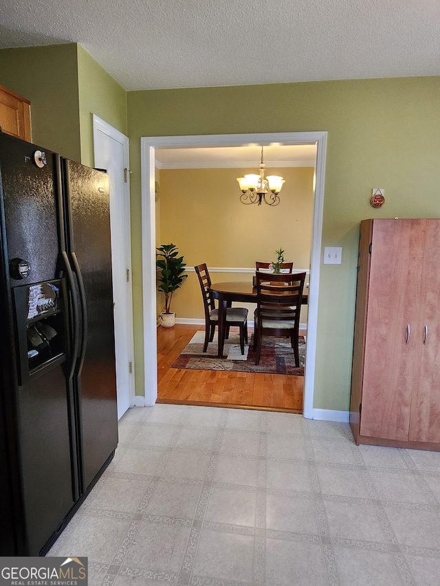 kitchen featuring black fridge, light hardwood / wood-style flooring, hanging light fixtures, an inviting chandelier, and a textured ceiling