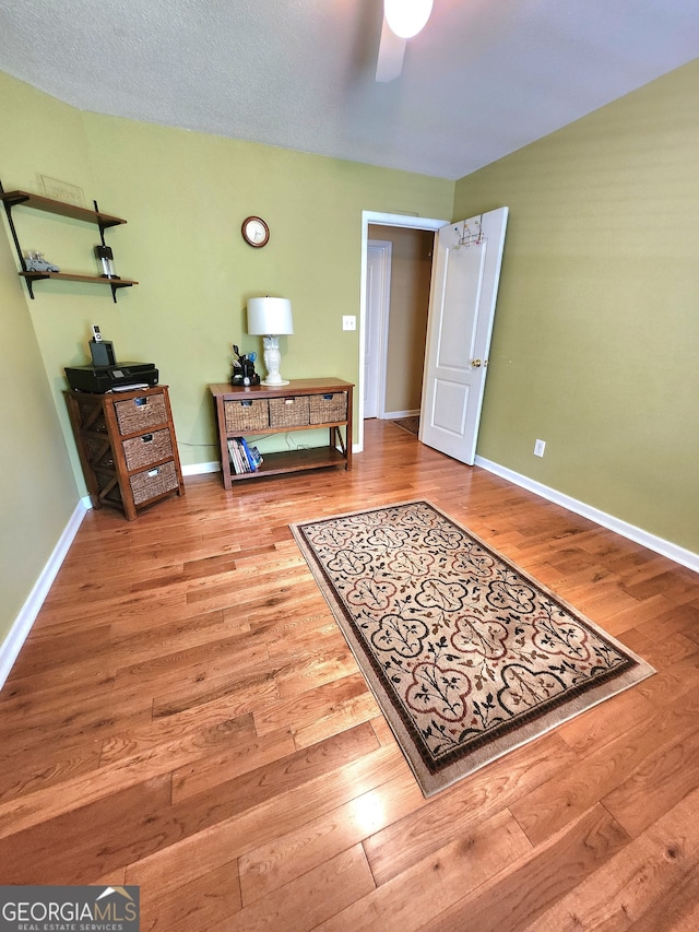 bedroom featuring ceiling fan, hardwood / wood-style flooring, and a textured ceiling