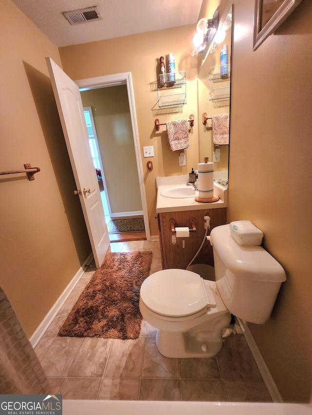 bathroom with vanity, toilet, a textured ceiling, and tile patterned flooring