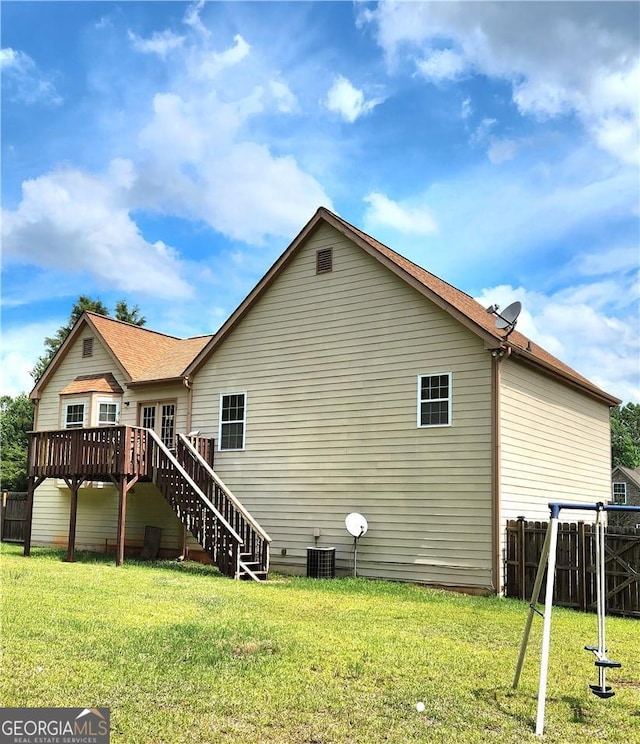 back of house featuring central AC, a wooden deck, and a lawn