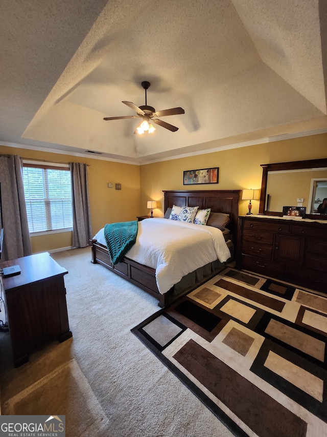 carpeted bedroom featuring ceiling fan, a raised ceiling, a textured ceiling, and ornamental molding