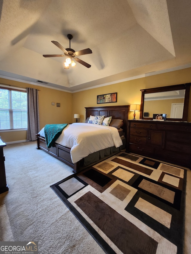 bedroom with a textured ceiling, a tray ceiling, carpet floors, and ceiling fan