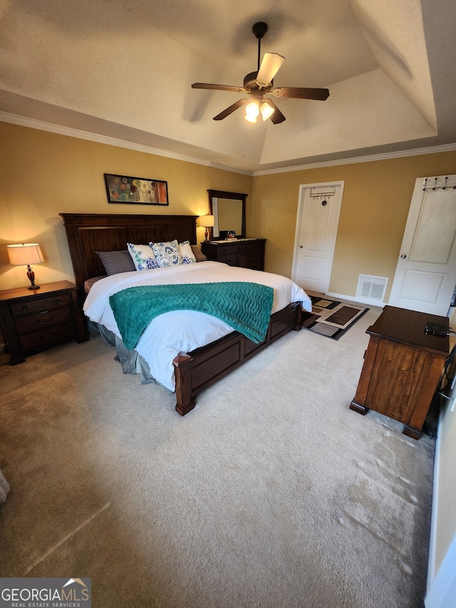 carpeted bedroom with ornamental molding, a tray ceiling, and ceiling fan