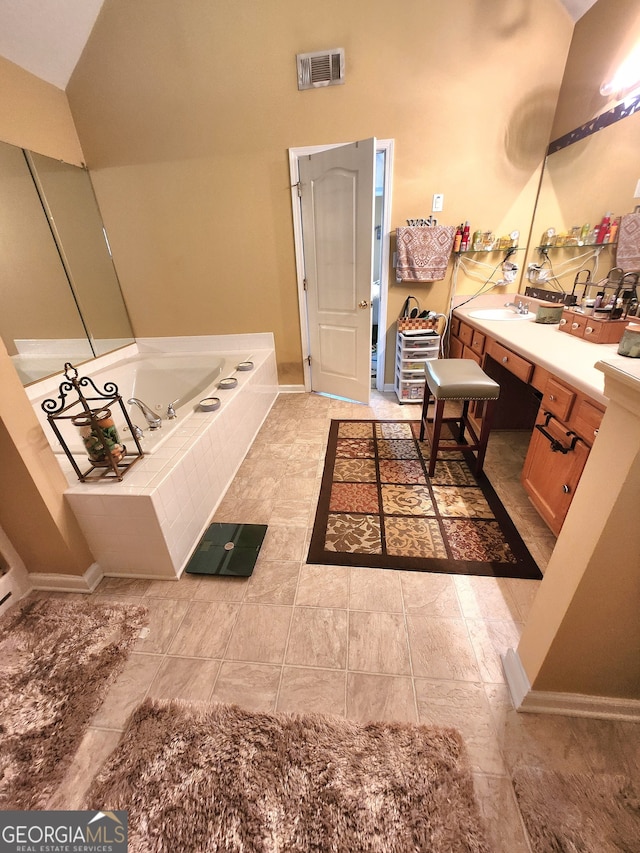 bathroom with vanity, a relaxing tiled tub, tile patterned floors, and vaulted ceiling