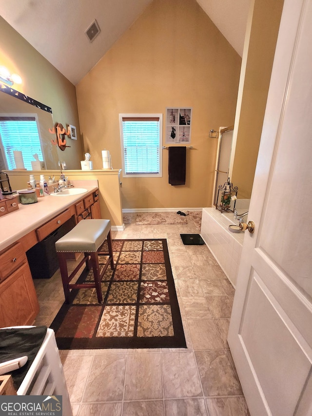 bathroom with vanity, high vaulted ceiling, and a bath