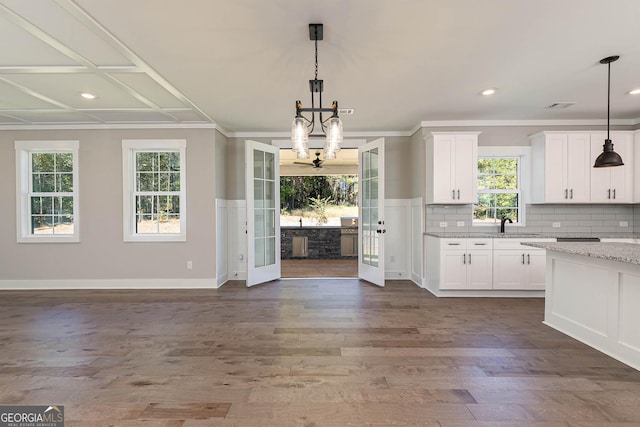 kitchen with white cabinets, french doors, decorative light fixtures, and light stone countertops