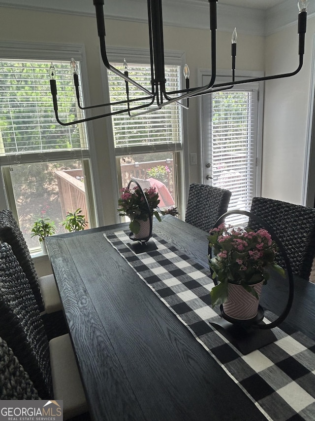 dining area with plenty of natural light, an inviting chandelier, and ornamental molding