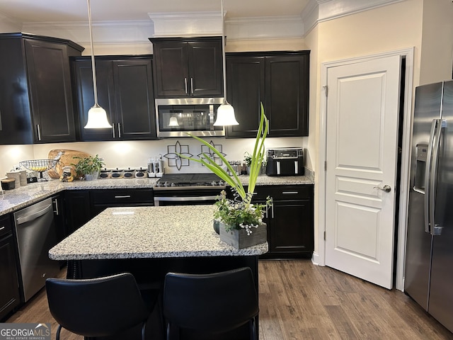 kitchen with a kitchen breakfast bar, wood-type flooring, pendant lighting, a kitchen island, and stainless steel appliances