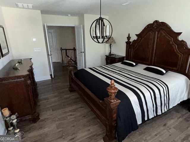 bedroom with dark hardwood / wood-style floors and an inviting chandelier