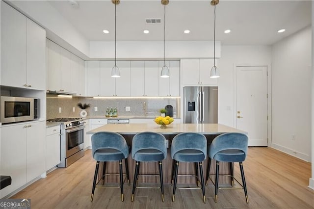 kitchen featuring pendant lighting, white cabinets, and appliances with stainless steel finishes