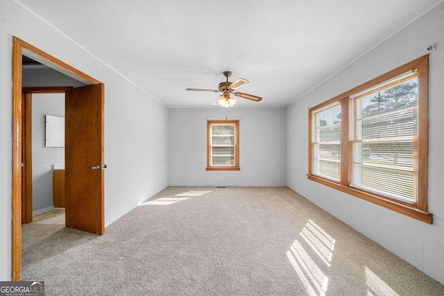 carpeted empty room featuring ornamental molding and ceiling fan