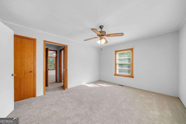 carpeted empty room featuring ceiling fan and crown molding