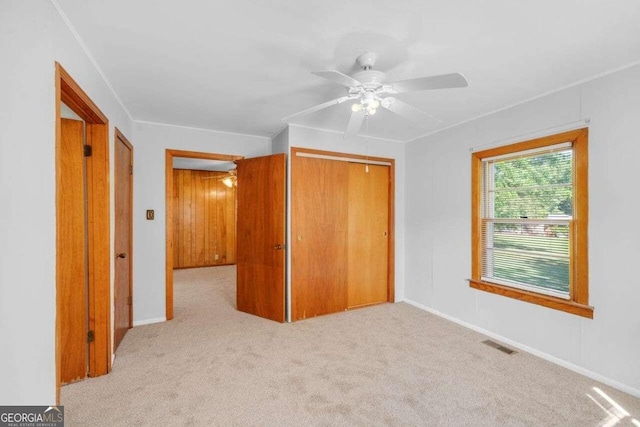 unfurnished bedroom with ornamental molding, a closet, carpet floors, and ceiling fan