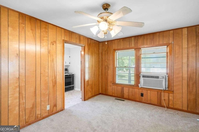 unfurnished bedroom featuring ceiling fan, cooling unit, light carpet, wood walls, and ensuite bathroom