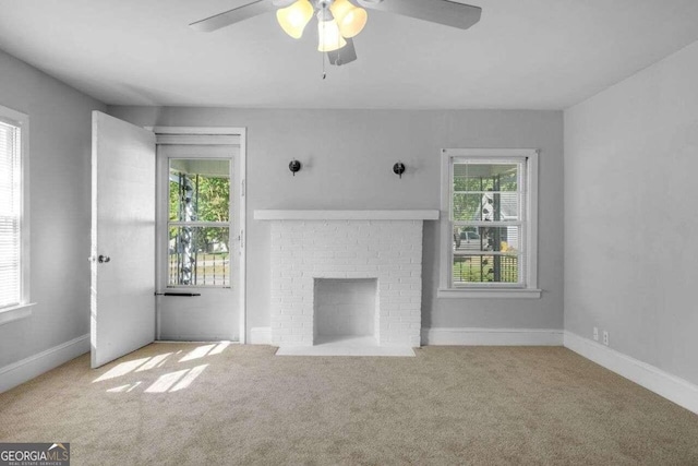 unfurnished living room featuring a brick fireplace, light colored carpet, and ceiling fan