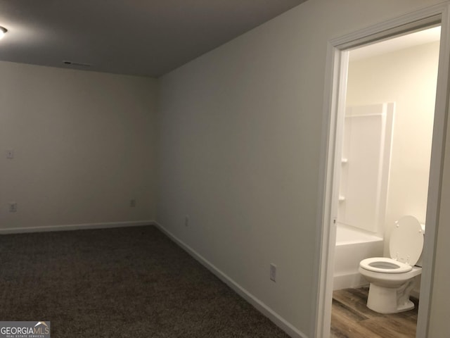 interior space with washtub / shower combination, wood-type flooring, and toilet