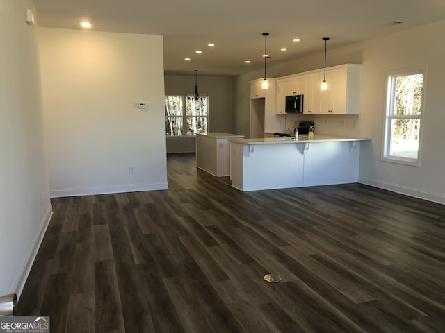 kitchen featuring dark wood-type flooring, hanging light fixtures, kitchen peninsula, stainless steel electric stove, and white cabinets