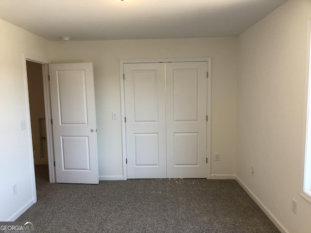 unfurnished bedroom with a closet and dark carpet