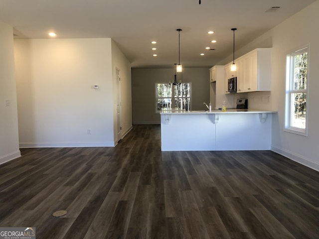 kitchen featuring kitchen peninsula, white cabinetry, dark hardwood / wood-style flooring, and pendant lighting