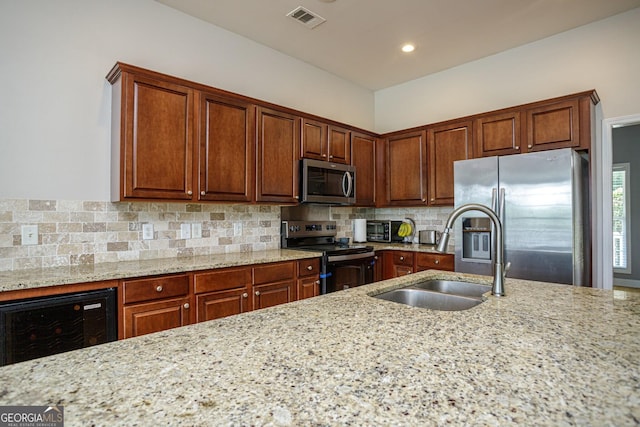 kitchen with light stone countertops, sink, tasteful backsplash, wine cooler, and appliances with stainless steel finishes