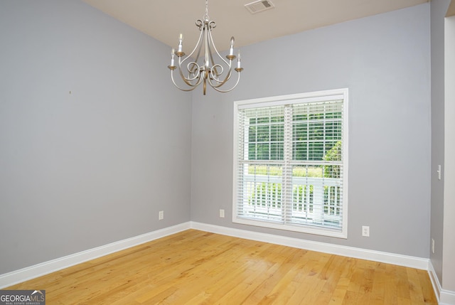 unfurnished room featuring hardwood / wood-style floors and a notable chandelier