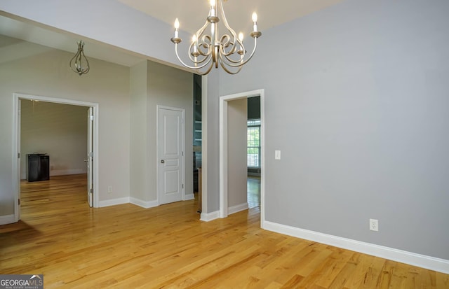 unfurnished dining area with a notable chandelier and light hardwood / wood-style flooring