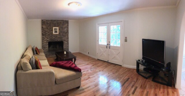 living room with light hardwood / wood-style floors, crown molding, a fireplace, and brick wall