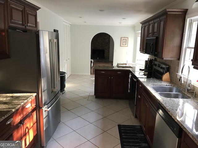 kitchen featuring stainless steel appliances, stone countertops, sink, tasteful backsplash, and light tile floors