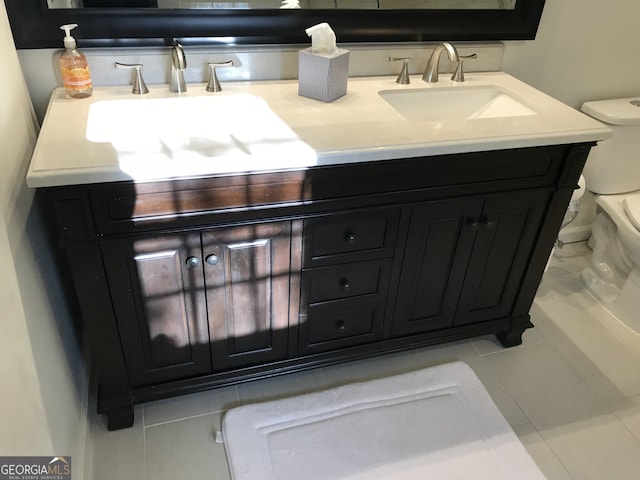 bathroom with double sink vanity, toilet, and tile floors