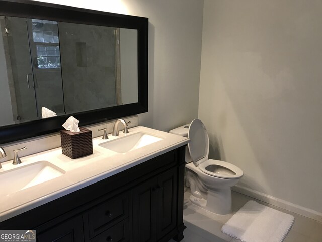 bathroom with a shower with shower door, tile flooring, double sink vanity, and toilet