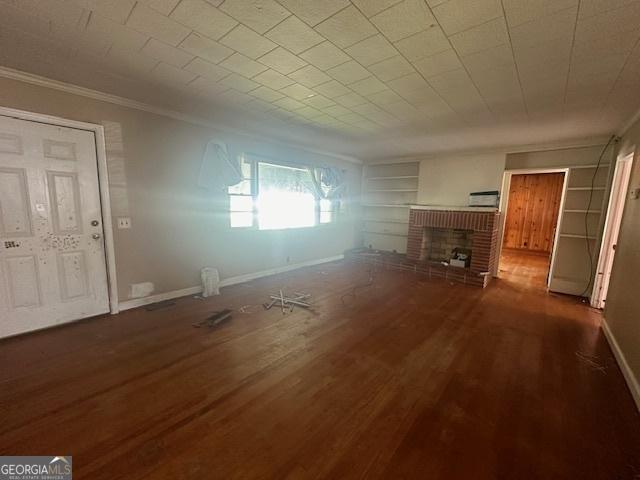 151 Lorrie St, Sardis, GA 30456 - unfurnished living room with crown molding, built in shelves, a fireplace, and wood finished floors