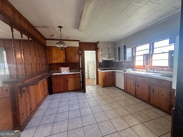 151 Lorrie St, Sardis, GA 30456 - kitchen with dishwasher, wooden walls, tile countertops, under cabinet range hood, and brown cabinetry